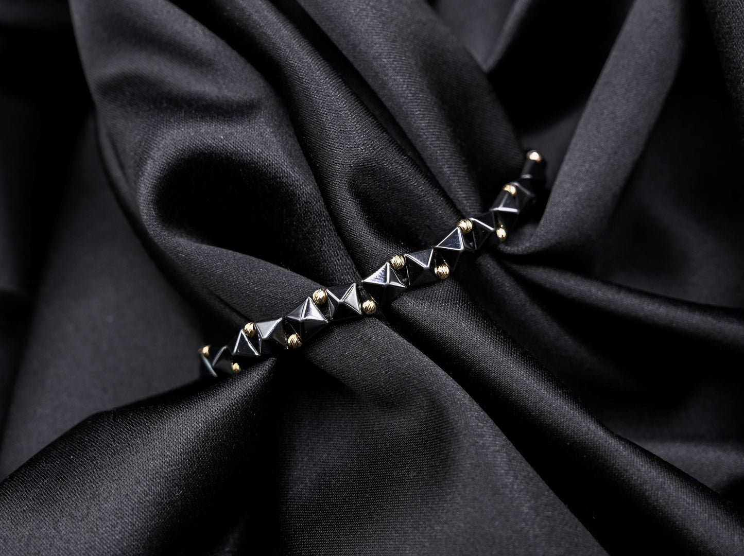 Gouden kralenarmband met geometrische, keramische kralen in antracietkleur