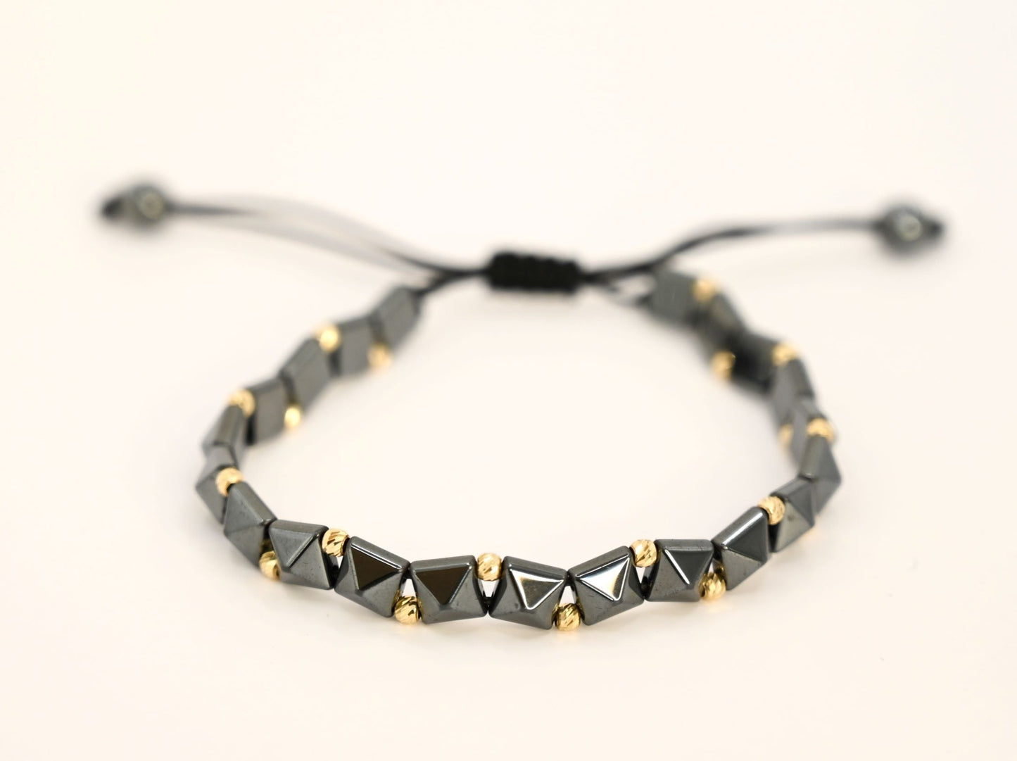 Gouden kralenarmband met geometrische, keramische kralen in antracietkleur