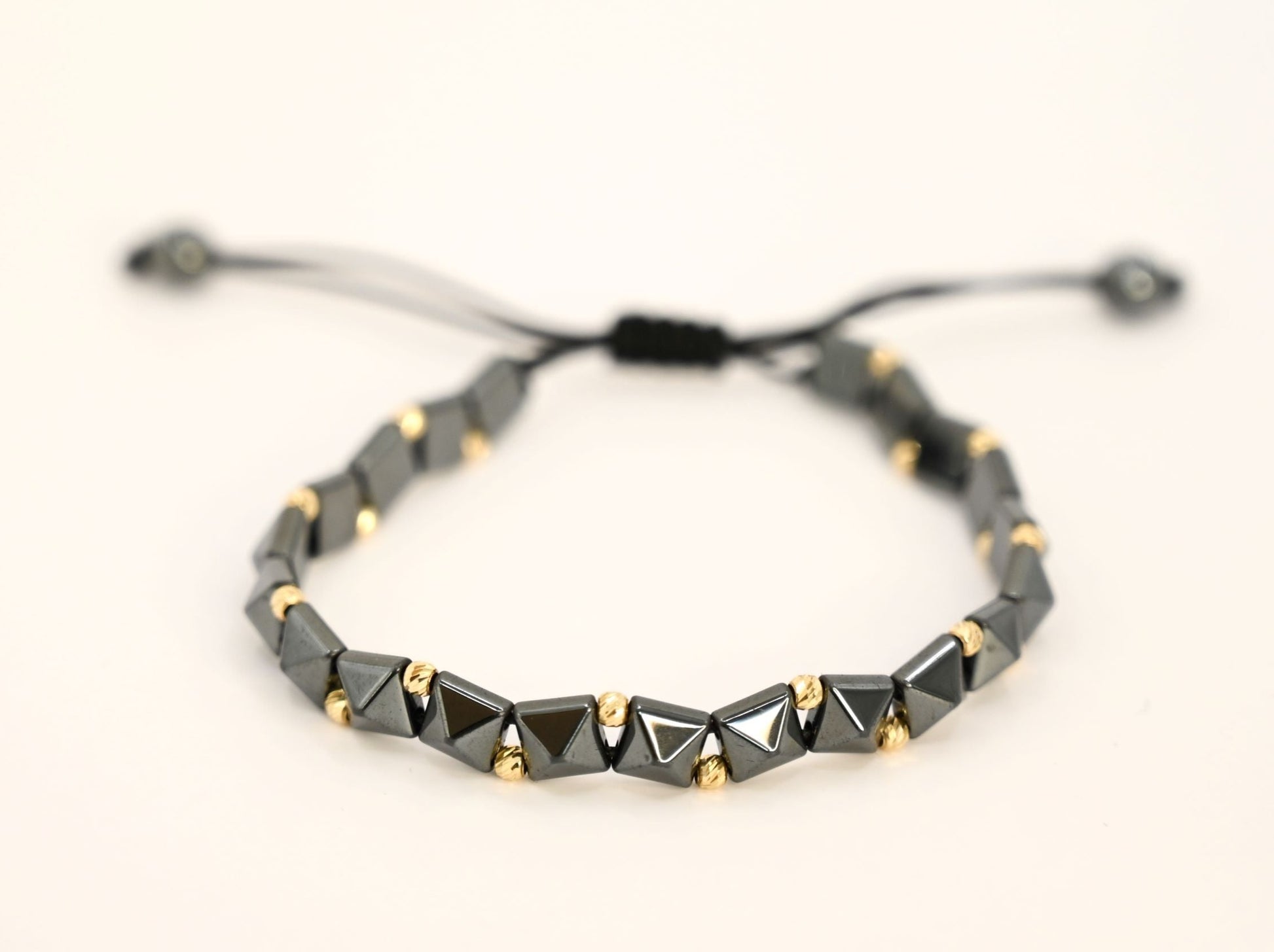 Gouden kralenarmband met geometrische, keramische kralen in antracietkleur