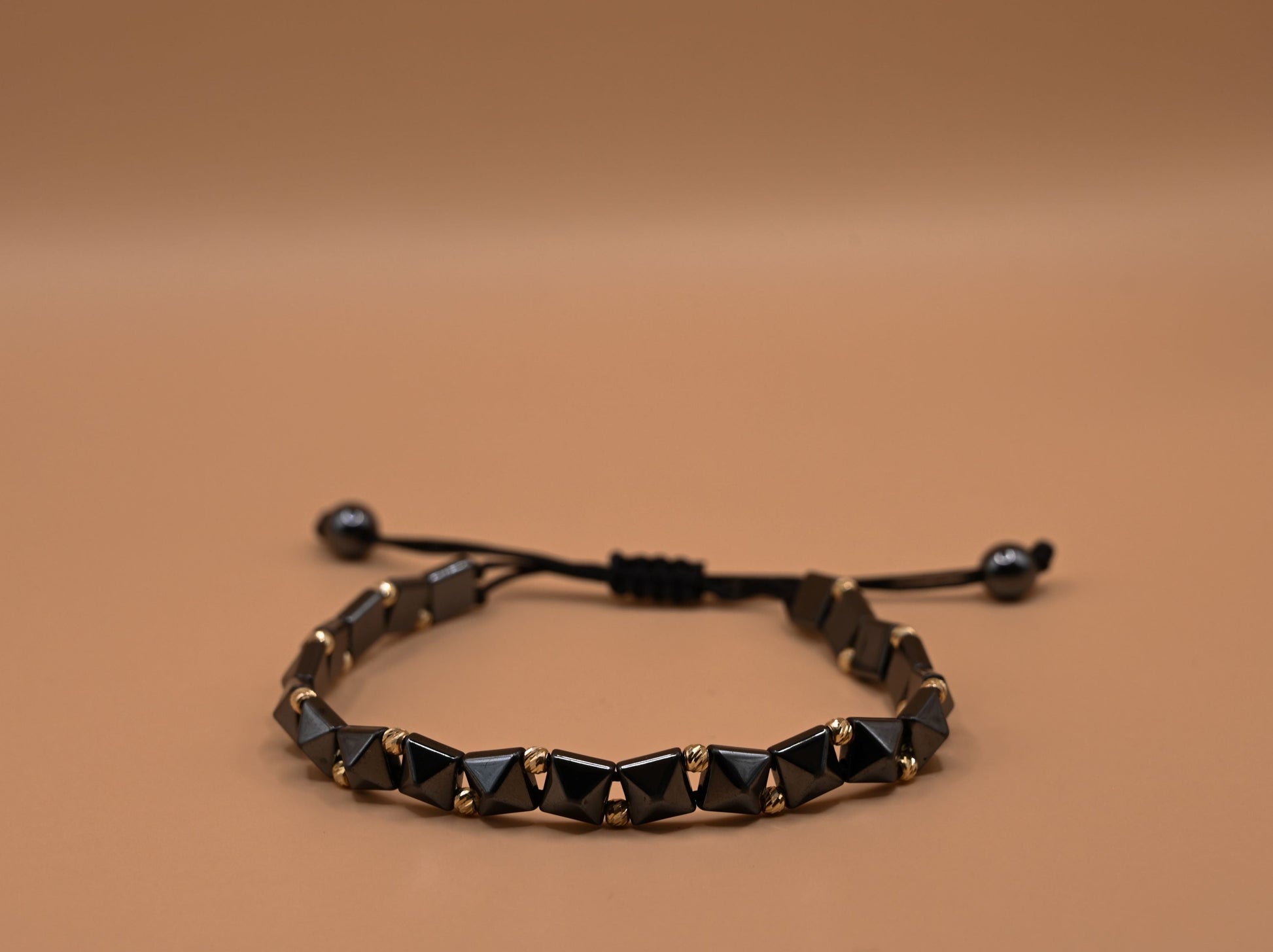 Gouden kralenarmband met geometrische, keramische kralen in antracietkleur