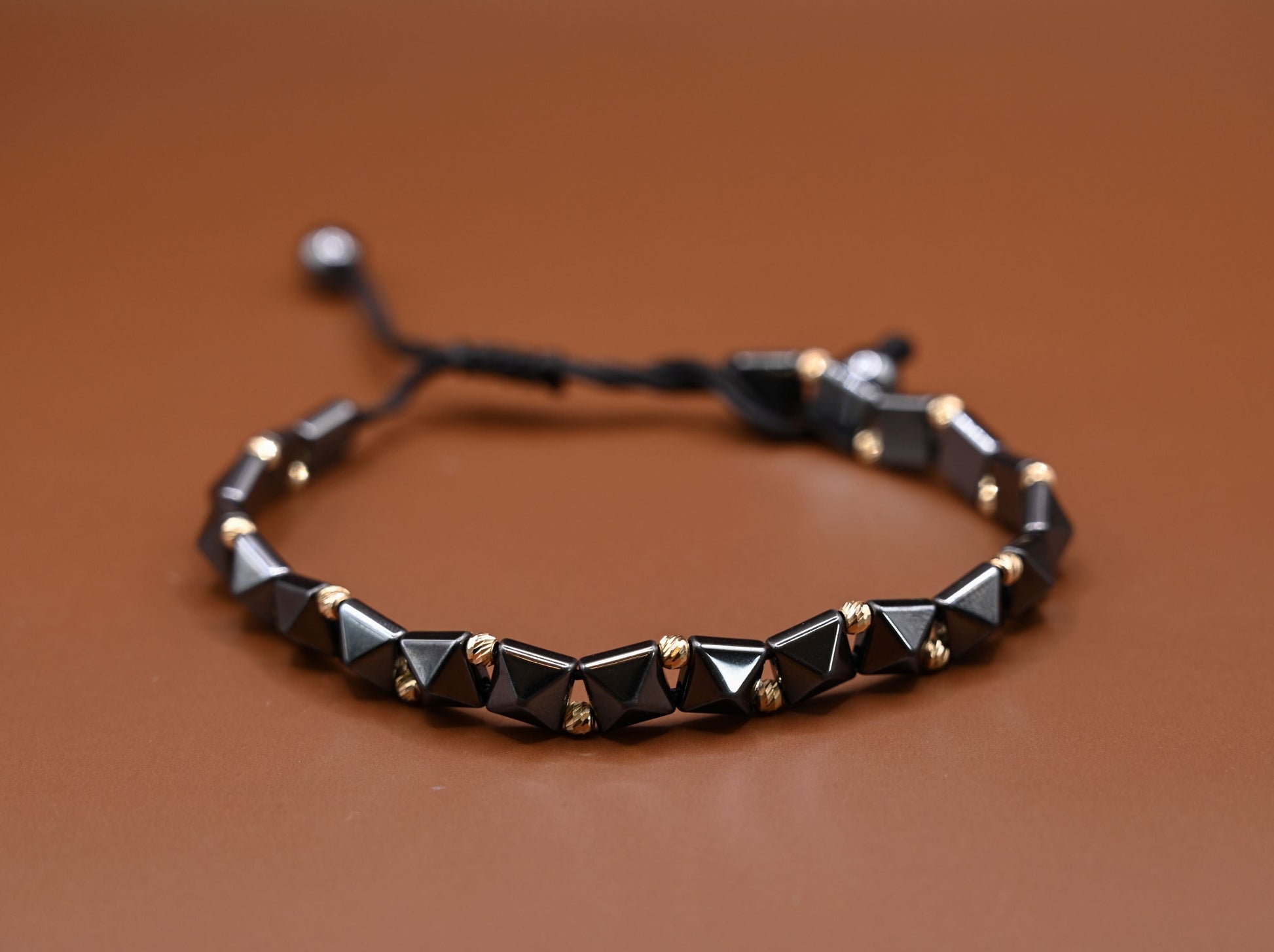 Gouden kralenarmband met geometrische, keramische kralen in antracietkleur