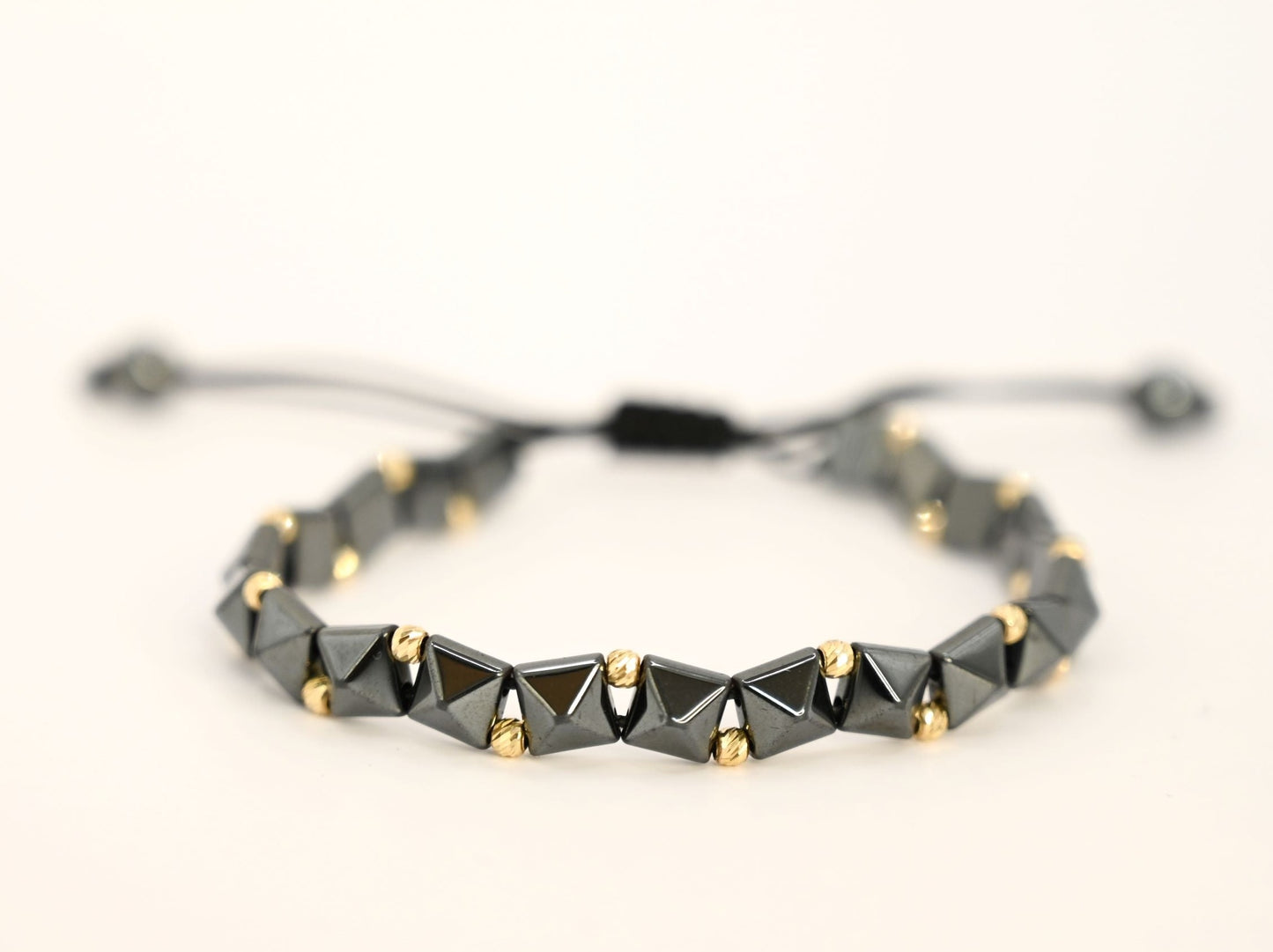 Gouden kralenarmband met geometrische, keramische kralen in antracietkleur