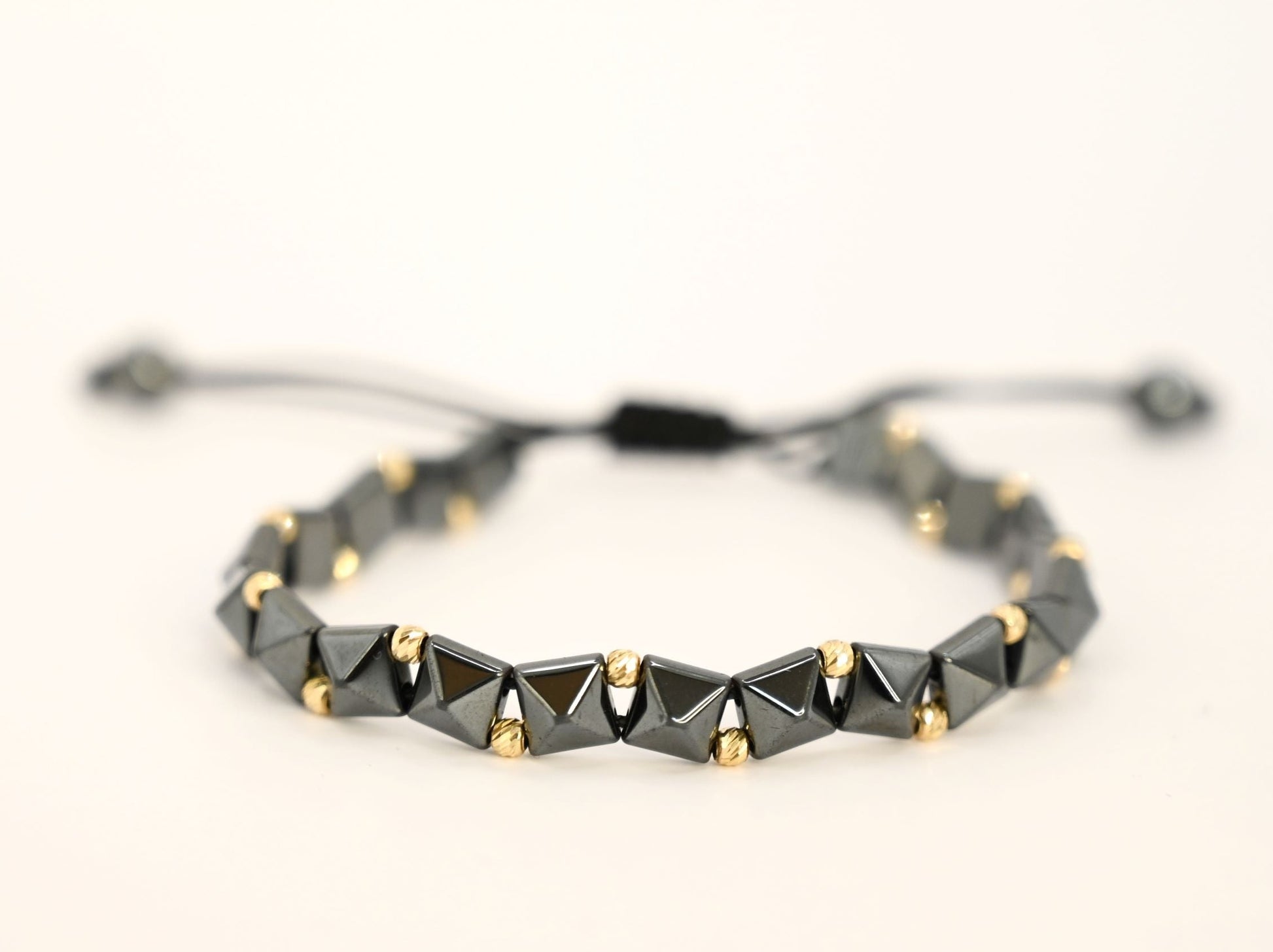 Gouden kralenarmband met geometrische, keramische kralen in antracietkleur